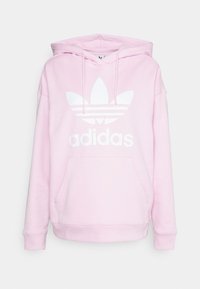 Rosa bomullshettegenser med frontlomme, snøring i hetten og stort hvitt Adidas-logo med tre striper og blomstermotiv.