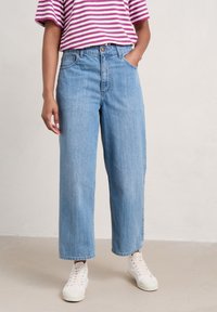Light blue wide-leg jeans with a high waist, featuring front pockets and a subtle wash, paired with a pink and white striped oversized T-shirt.