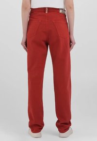 Punased denim püksid sirge lõikega, kõrge vöökoht ja kaks tagumist taskut. Kanga pind on sile.