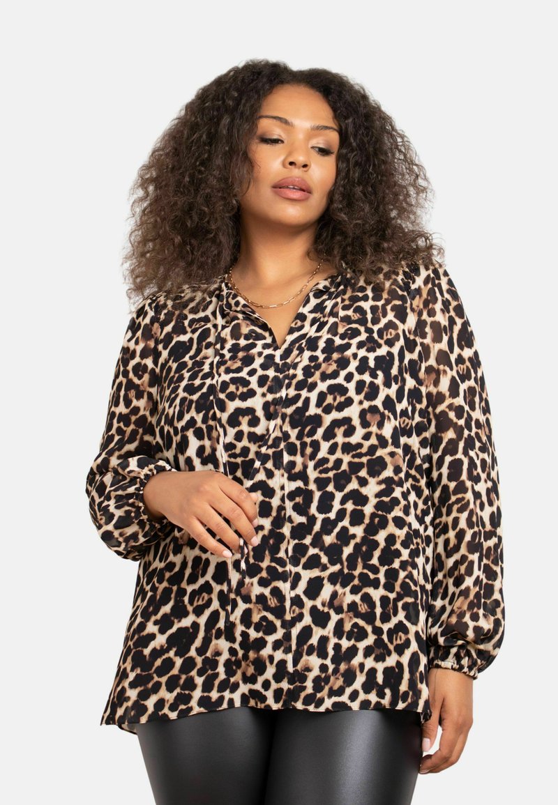 Blusa in stampa leopardata beige e nera, con chiusura a bottoni, maniche lunghe con polsini elasticizzati e vestibilità morbida.