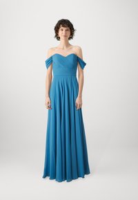 Dolga, lepršljiva obleka iz žive modre tkanine. Oblika brez naramnic z nagubanimi deli zgornjega dela in gladkim krilom. Eleganten in lahek material.