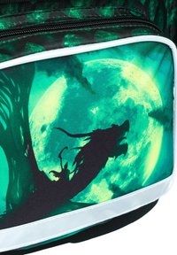 Czarny i zielony plecak z sylwetką smoka na tle świecącego zielonego księżyca, z białym wykończeniem i zamkiem błyskawicznym.