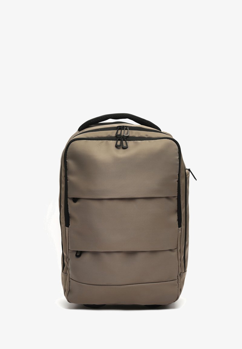 Prizma nahrbtnik taupe barve z več zadrg, črnimi zadrge držali in oblazinjenim zgornjim ročajem na belem ozadju.