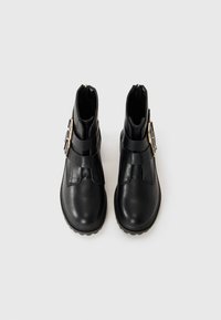 Black leather ankle boots featuring a rounded toe, dual straps with a gold buckle accent, and a textured rubber sole.