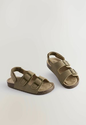 Olivové sandále s tromi nastaviteľnými popruhmi, textúrovanou stielkou a hnedou korkovou podrážkou. Otvorený dizajn vzadu pre ventiláciu.