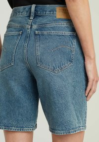 Lichte blauwe denim shorts met een vervaagde afwerking. Heeft een hoge taille, vijf zakken en contrasterende stiksels. Leren patch op de achterkant.