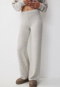 Pantalones de pierna ancha de color gris claro, fabricados en una tela suave con cintura elástica. Presentan una textura lisa y un diseño minimalista.