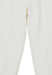 Pantaloni bianchi su misura con una texture liscia, dotati di vita media e piega su misura lungo la parte anteriore di ciascuna gamba.