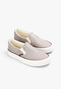 Slipschuhe mit einem schimmernden, hellrosa Stoffobermaterial, cremefarbener Fütterung und weißen Gummisohlen, ausgestattet mit elastischen Seitenpaneelen und einem schwarzen Rand.