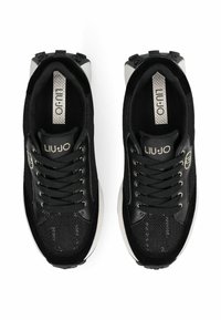 Baskets noires avec une tige en mesh et des accents en daim, une semelle blanche texturée et un logo détaillé sur la languette.