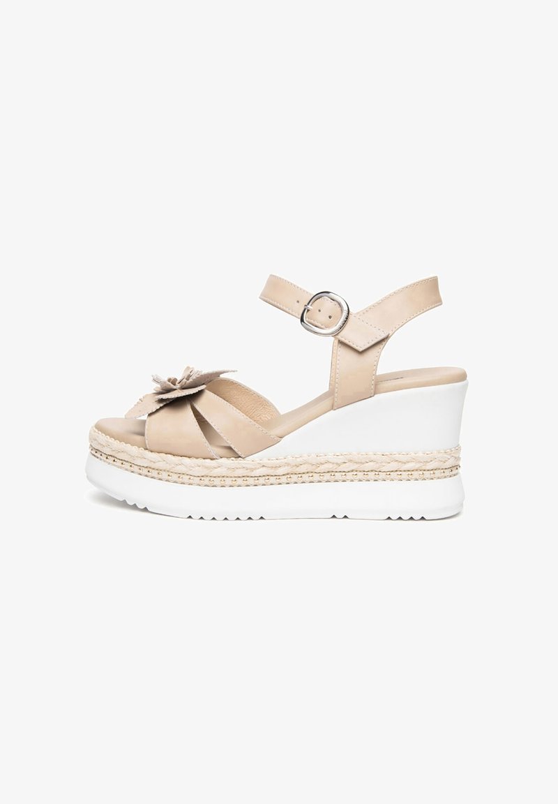 Sandale compensée beige avec bride à la cheville et boucle, bout ouvert, ornement fleur décoratif, et semelle plateforme blanche avec détails tressés.