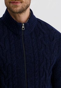 Marineblauer gestrickter Pullover mit hohem Kragen, kabelmuster, vollständiger Reißverschluss und strukturiertem Stoff.