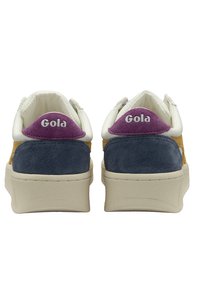 Sneaker Gola con un corpo in suede giallo, tallone blu navy, dettagli bianchi e una toppa in suede viola sul retro con il nome del marchio.