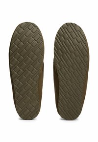 Zapatos de ante marrón con suelas de goma texturizadas, que cuentan con un patrón de diamantes para mejorar el agarre. El diseño es de perfil bajo con bordes redondeados.