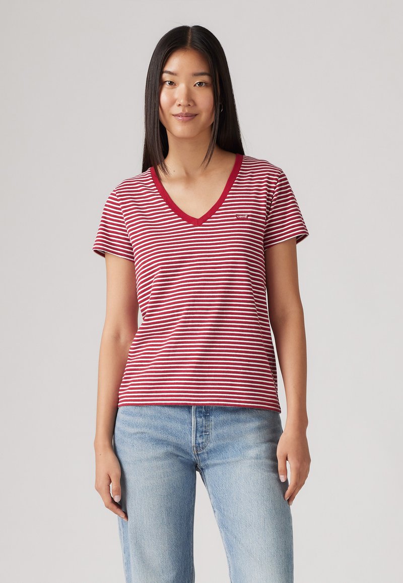 Camiseta de rayas rojas y blancas con escote en V y mangas cortas, hecha de una tela suave. Presenta un pequeño logo en el pecho.