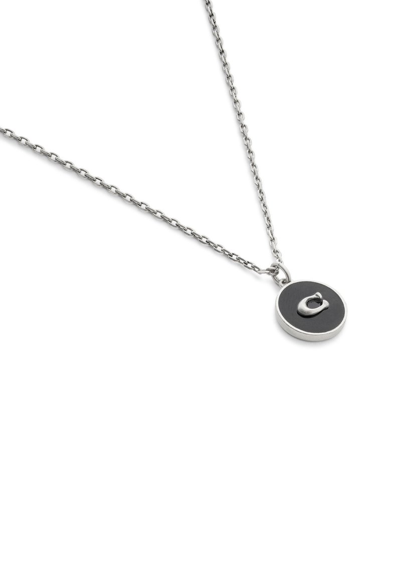 Silberne Halskette mit einem runden Anhänger, der ein schwarzes Zentrum und ein stilisiertes silbernes Detail aufweist. Die Kette hat ein zartes, verbundenes Design.