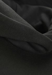 Svart tyg med en jämn textur, med en vikt design som framhäver dess sträckbarhet och enhetliga färg. Inga mönster eller accenter synliga.