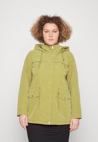 Giacca impermeabile verde oliva con cappuccio, chiusura a zip, tasche frontali e coulisse regolabili in vita e al collo. Texture liscia.