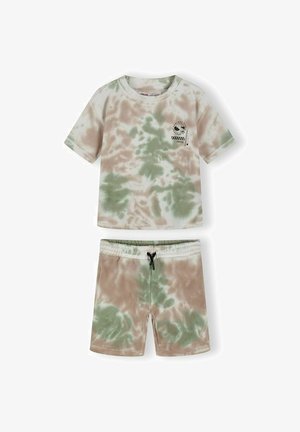 Ensemble chemise à manches courtes et short tie-dye vert et beige, avec un petit motif graphique noir sur la poitrine de la chemise.