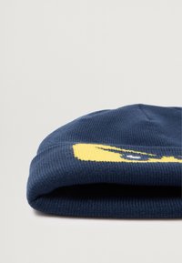Námornícky pletený kulich s žlutým grafickým designem. Textura je žebrovaná a design obsahuje odvážné tvary a linie.
