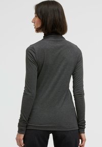 Long-sleeve turtleneck top in dark gray, made of soft, stretchy material, featuring a fitted silhouette and smooth texture.