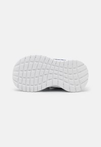 Semelle de chaussure en caoutchouc blanc avec des motifs de grip texturés et des sections surélevées pour l'adhérence. Design épuré avec une finition lisse.