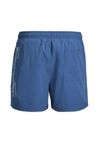 Maillots de bain pour hommes bleus avec taille élastique, poche arrière du côté droit, et texte de logo vertical blanc sur la jambe gauche.