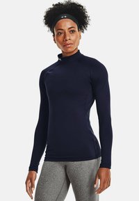 Dlhý rukáv námornícky atletický dres s vysokým golierom, priliehajúcim dizajnom a hladkým materiálom. Obsahuje logo Under Armour na krku.