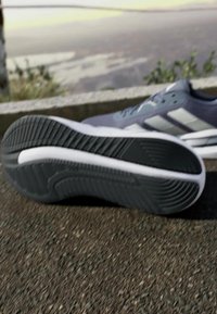 Sports shoe with mesh upper in dark gray, white accents, and rubber outsole featuring a textured pattern for grip.