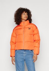 Giacca a vento arancione con colletto alto, chiusura con zip e dettaglio del logo nero. Il tessuto ha una finitura lucida e testurizzata ed è di design cropped.