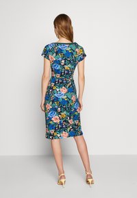 Bloemige jurk heeft een getailleerd ontwerp met kapmouwen, een donkere achtergrond, levendige meerkleurige bloemen en valt tot halverwege de kuit.