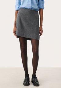Grå uld mini nederdel med en asymmetrisk kant. Sammen med sorte strømpebukser og chunky sorte loafers, hvilket skaber et tekstureret lagdelt look.