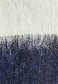 Textuurgebreide stof met een verlopen van wit, lichtgrijs en donker marineblauw. Zacht, pluizig uiterlijk met fijne vezels.