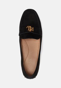 Svart mockason i mocka med rund tå, med en guldig "RL"-logotyp framtill. Insidan har en slät tanfärgad foder med perforerade detaljer på fotbädden.