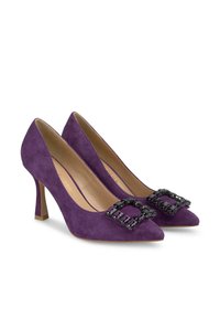 Tacchi alti in suede viola con design a punta, caratterizzati da una grande fibbia nera con gioielli sul collo del piede e un tacco sottile.