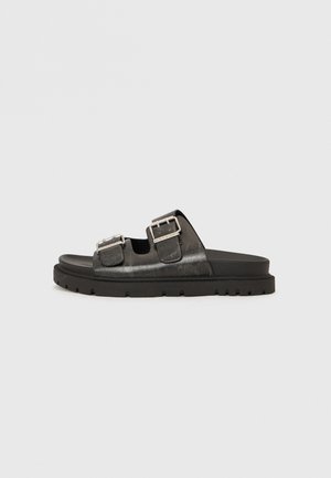 Sorte læder slidesandaler med to justerbare spænder, en tekstureret overflade og en tyk, rillede gummisål.