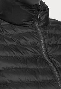 Svart puffjacka med hög krage, horisontell quiltad mönster och dragkedja fram. Har en glansig finish och kontrasterande sömmar på dragkedjan.