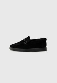 Sorte slip-on sko med overdel i semsket skinn, faux pelsfôr og minimalistisk design. Har dekorativ søm og en metalldetalj.