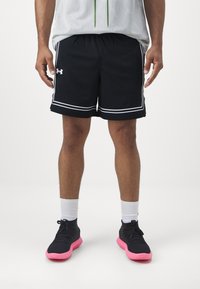 Pantalones cortos deportivos negros con detalles en blanco, textura de malla y un ajuste holgado, combinados con zapatillas negras con suelas rosas y calcetines blancos.