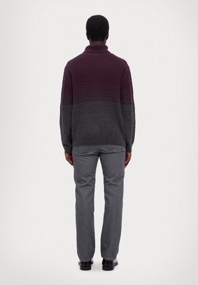 Pull en maille bordeaux et gris avec un col montant, design en dégradé texturé, associé à un pantalon droit gris et des chaussures noires.