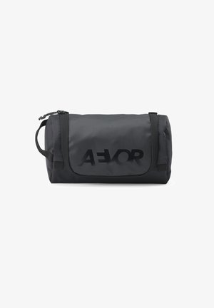 Schwarze kompakte Reisekosmetiktasche mit Griff, Klappenverschluss und AEVOR-Logo auf der Vorderseite.