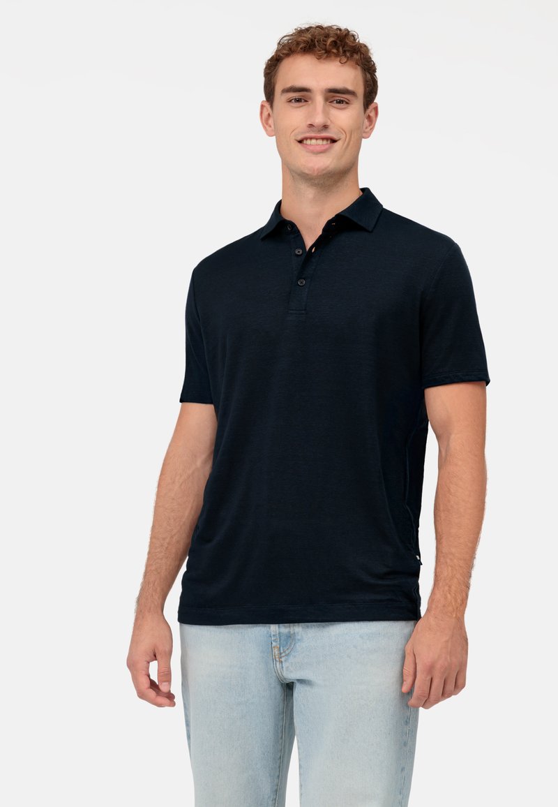 Marineblaue Poloshirt aus weichem Stoff, mit einer Dreiknopf-Leiste, kurzen Ärmeln und seitlichen Schlitzen für Bewegungsfreiheit.