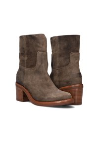 Brown suede ankle boots with a tapered shape, featuring a stacked wooden heel and a smooth leather sole. Subtle branding on the side.
