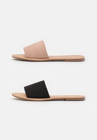 Deux paires de sandales à glissière : l'une en daim rose doux et l'autre en daim noir. Les deux présentent une semelle plate beige et un design ouvert à l'avant.