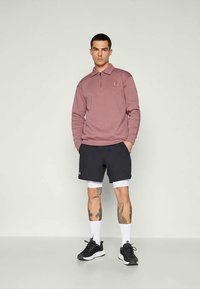 Pulover cu fermoar de culoare roz deschis, pantaloni scurți negri, șorturi albe, șosete albe, adidași negri. Prezintă tatuaje pe picioare, design simplu.