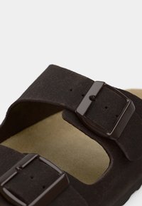 Καφέ σουέτ σανδάλι με δύο ρυθμιζόμενες αγκράφες, μαλακό πέλμα και ελαφρώς υφή στην επιφάνεια.