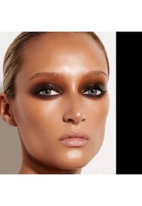 Nærbilde av et ansikt med solbrun hud, dyp brun øyesminke og rosa accenter. Definerte trekk, jevn tekstur og skinende lepper.