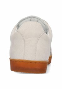 Beige mockaskoin med rundad bakdel, grå foder och en strukturerad brun gummisula. Slät yta utan synliga mönster eller hårdvara.