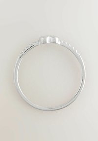 Cienki srebrny pierścionek z ostrym środkiem i małymi zaokrąglonymi elementami przypominającymi koraliki wzdłuż górnej części obrączki na jednolitym tle.