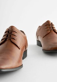 Brown leather shoes with a smooth finish, featuring a classic lace-up design, rounded toe, and black synthetic soles.